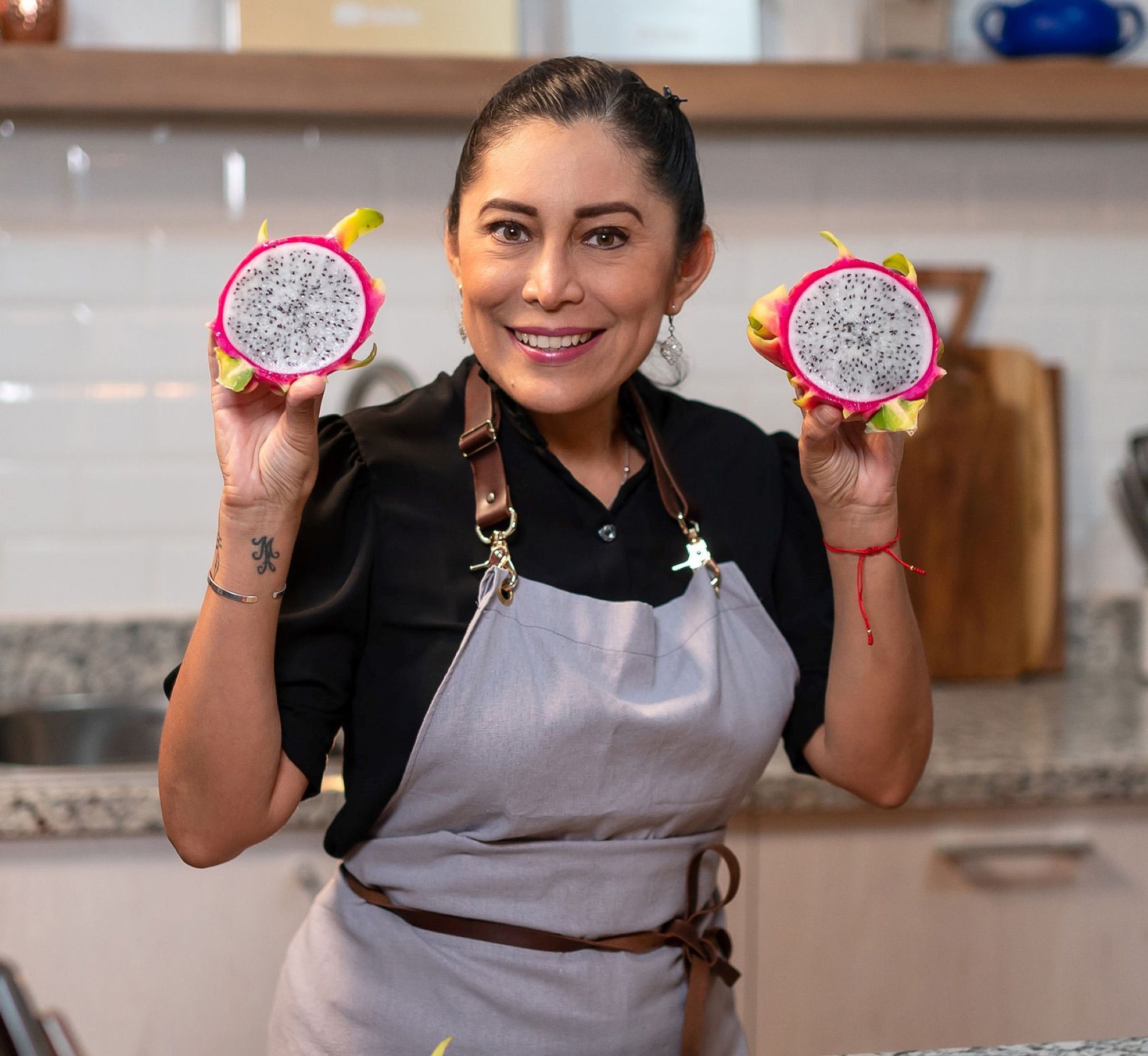 Addy sostiene dos mitades de pitahaya en su cocina